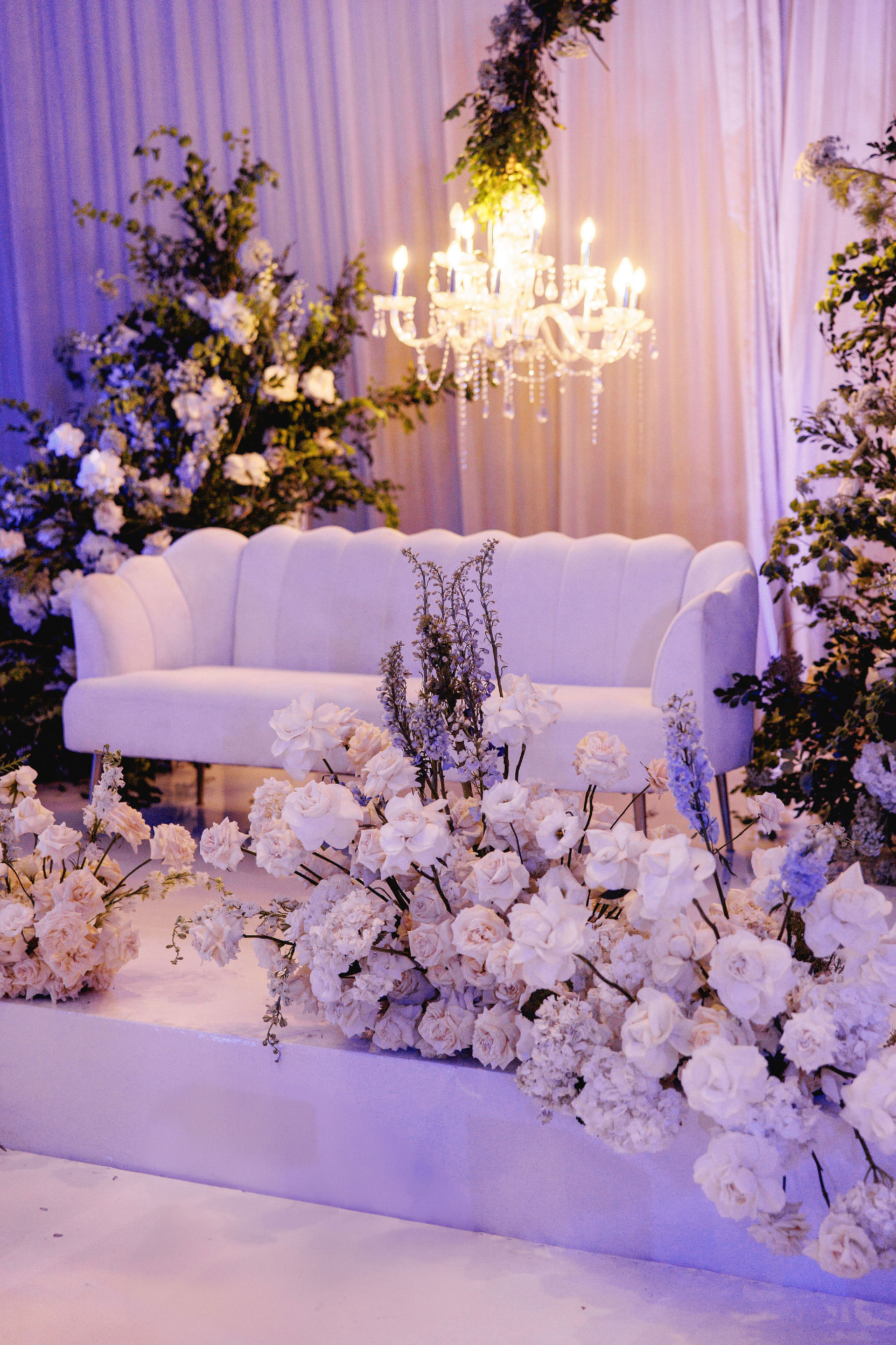 Lavender-lit reception lounge with chandelier and flowers