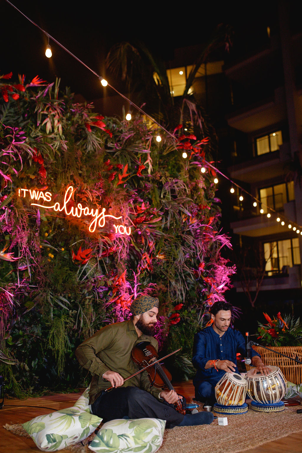 Sangeet musicians beneath a neon sign