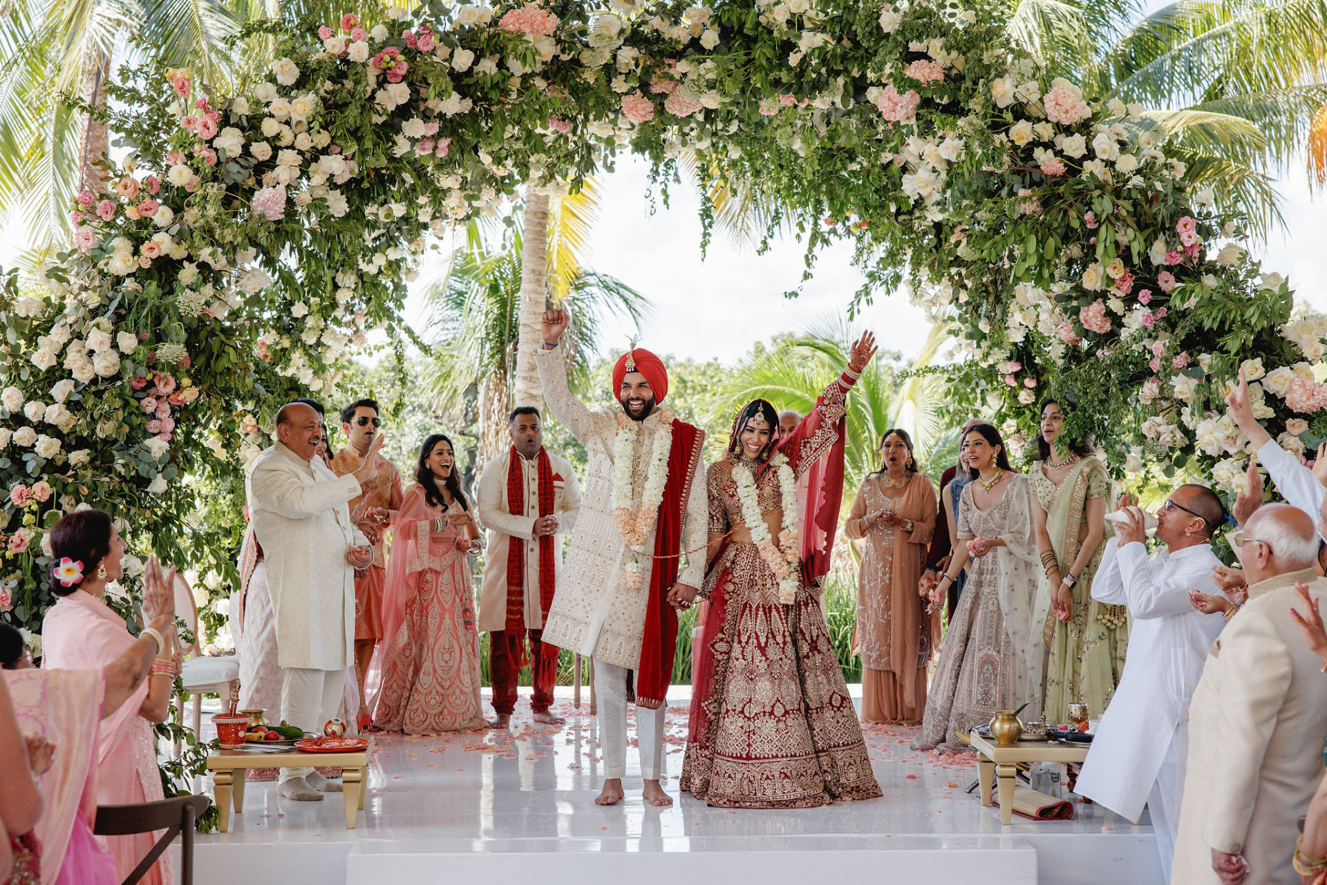Ceremony beneath a white and green floral arch