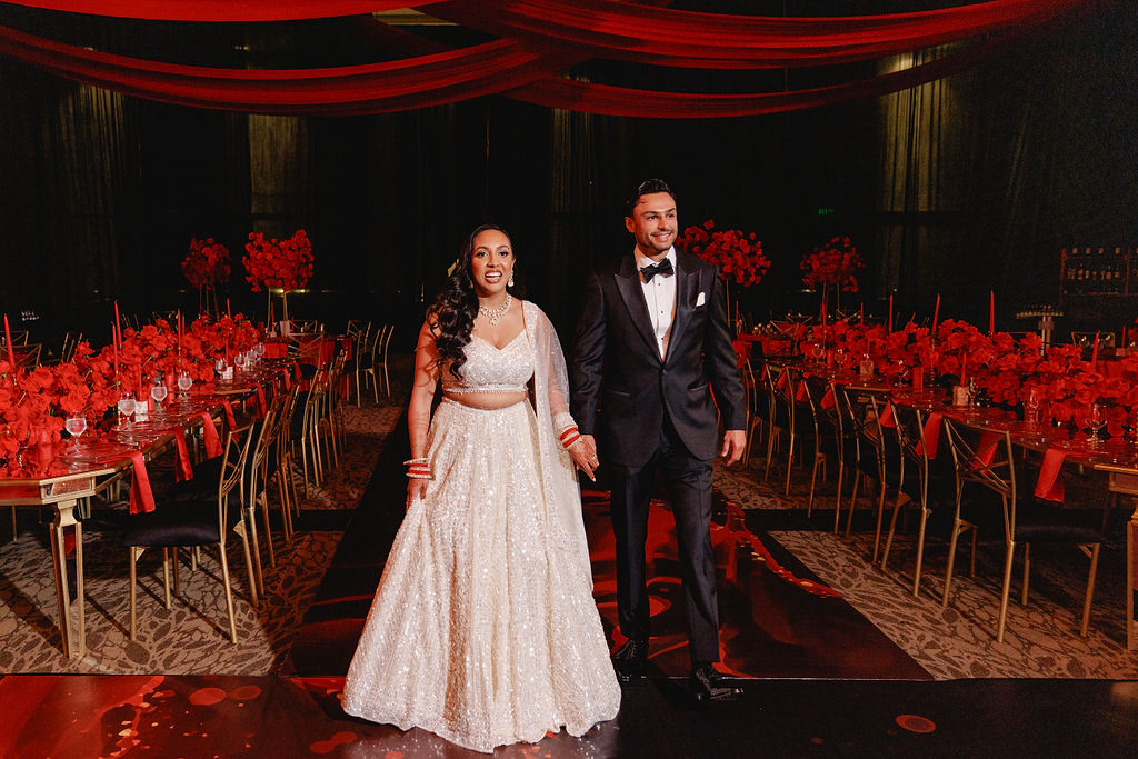 The couple entering the reception through red décor