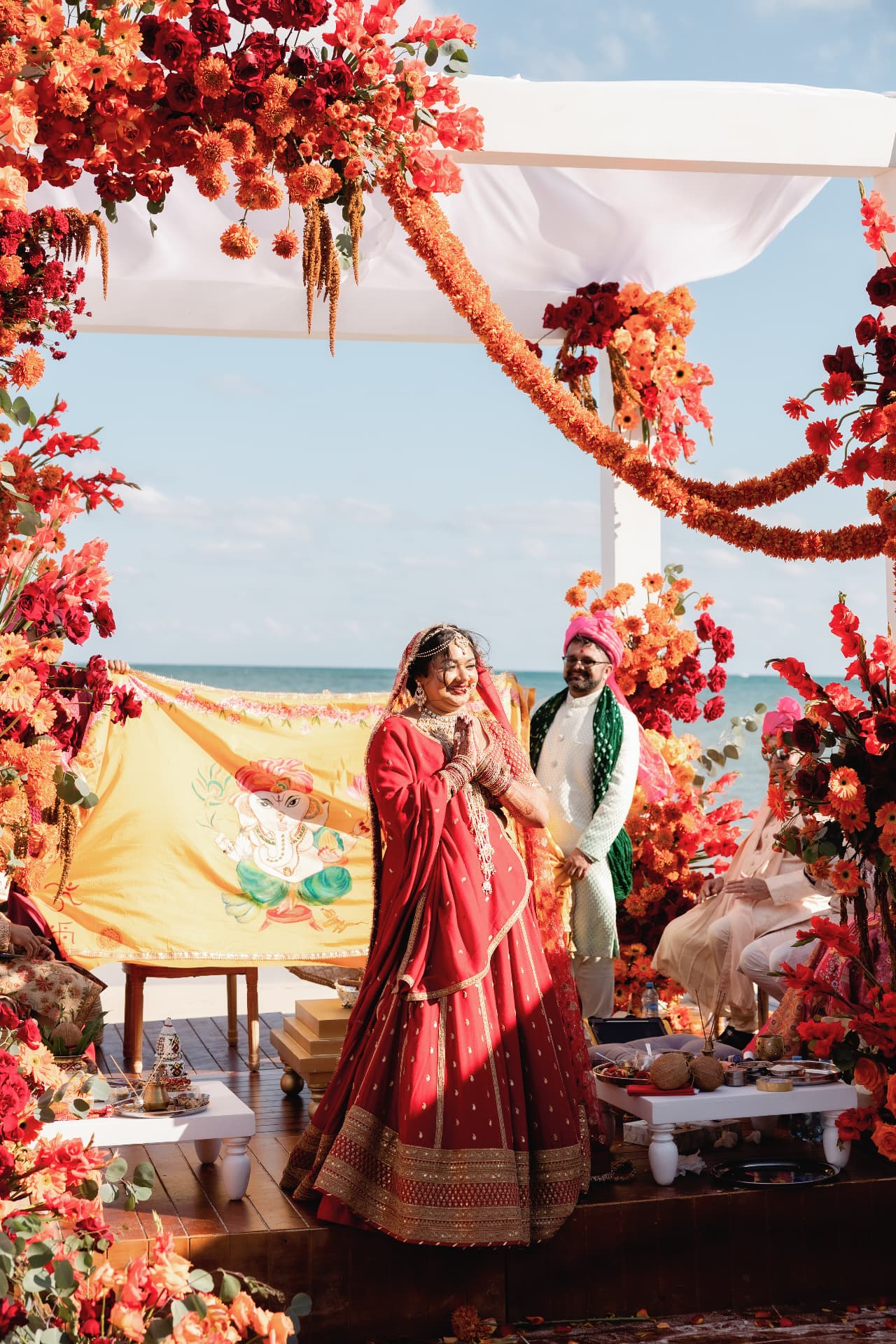 Ceremony with red and orange florals beside the ocean