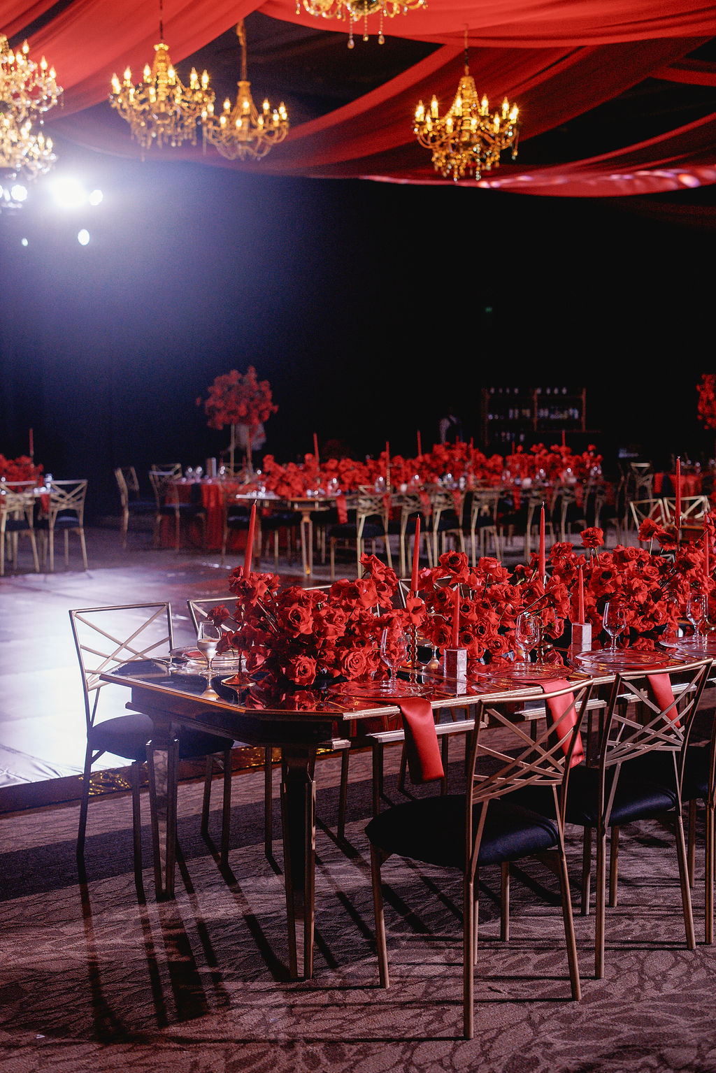 Red reception tablescape beneath chandeliers