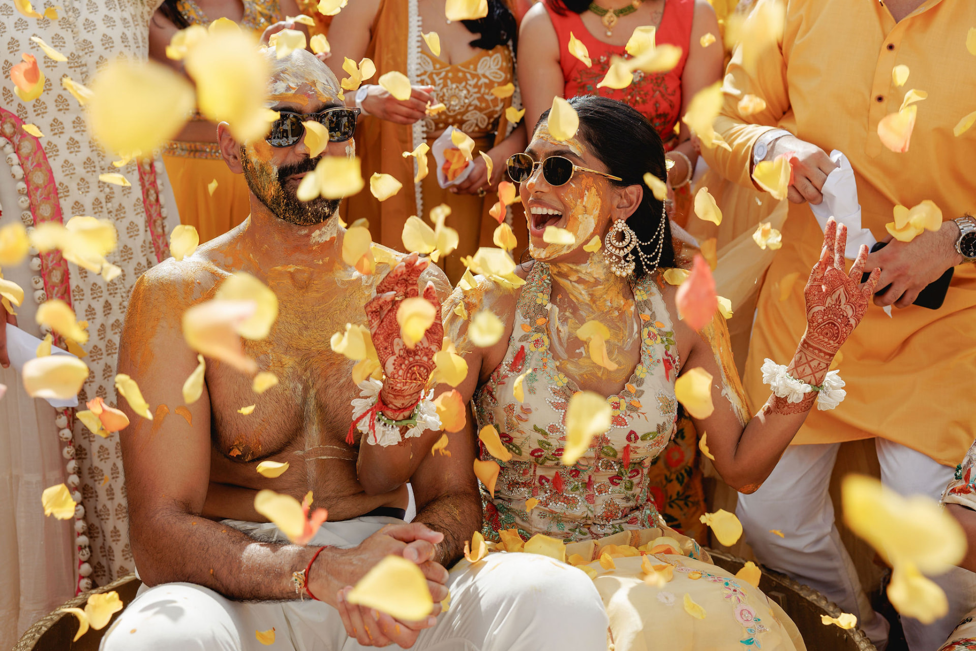 Prarthi surrounded by loved ones and falling petals during the Haldi