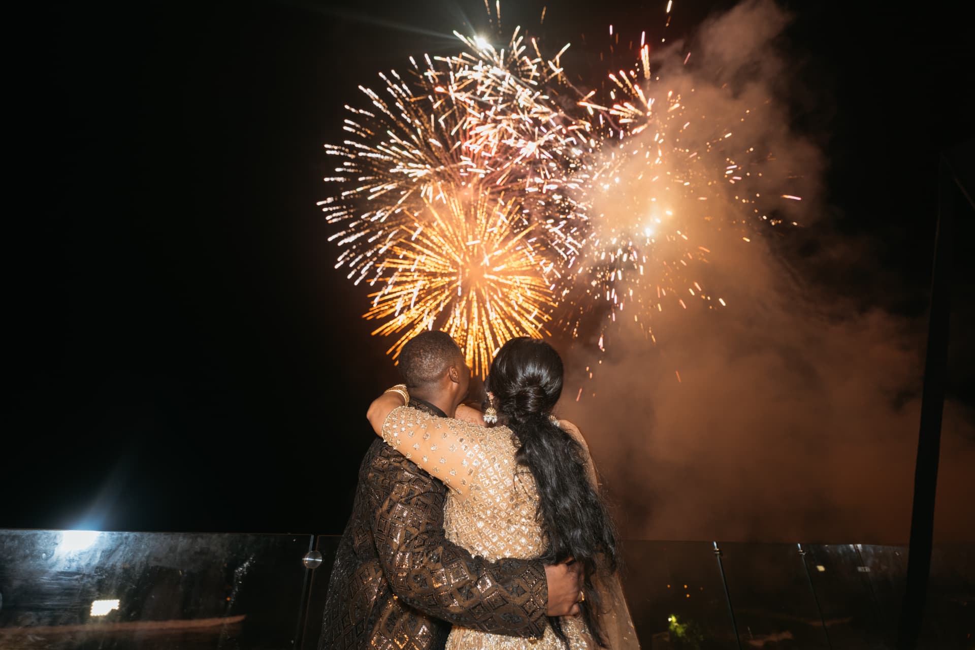 Cynthia and Azriel embracing beneath fireworks