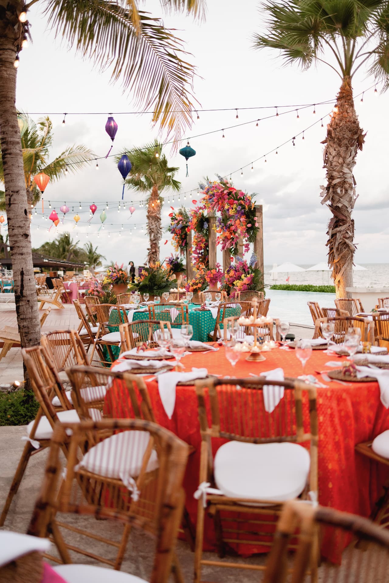 Colourful seaside tablescape with palms, lanterns and flowers