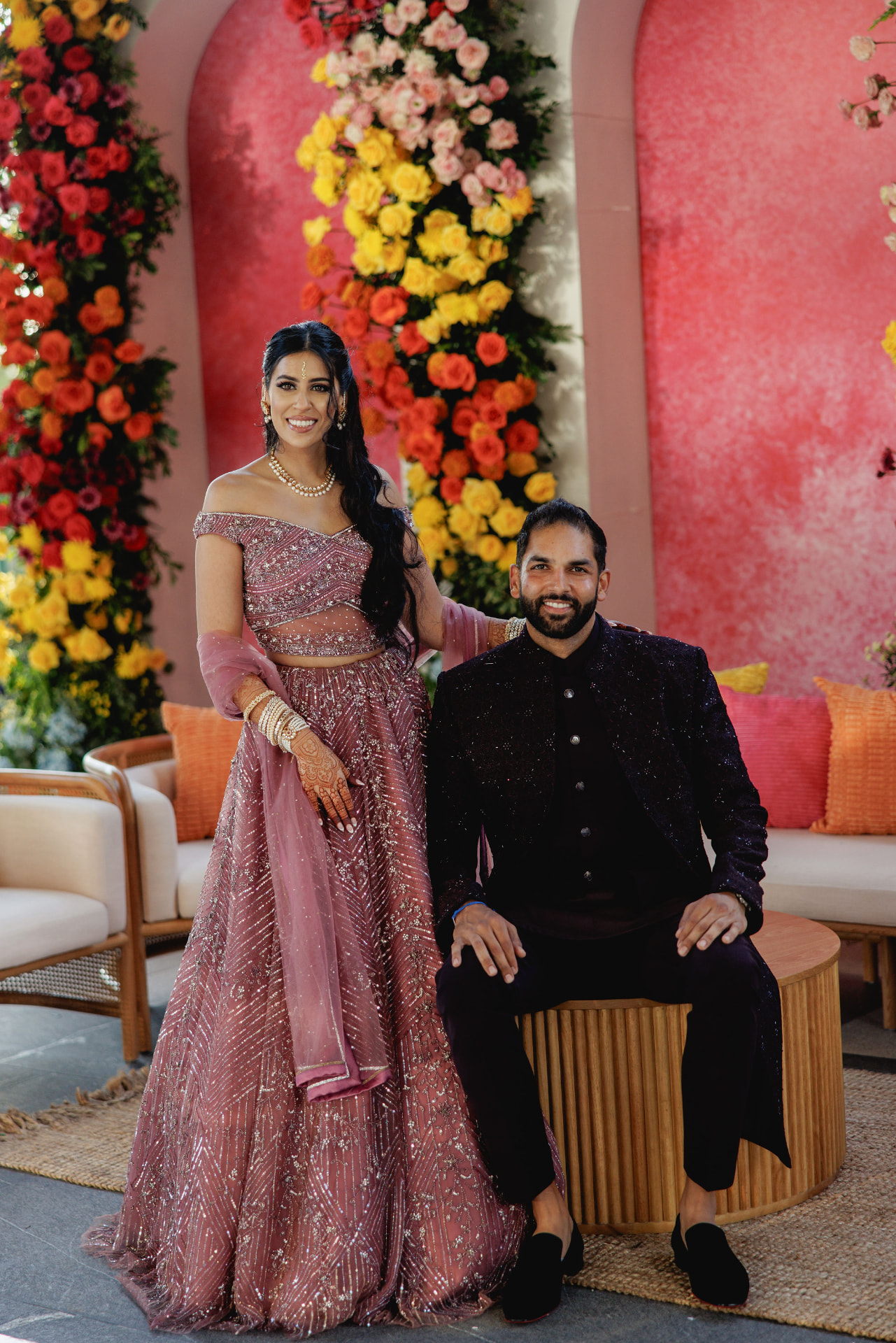 Ami and Kabir in pink attire before a floral backdrop