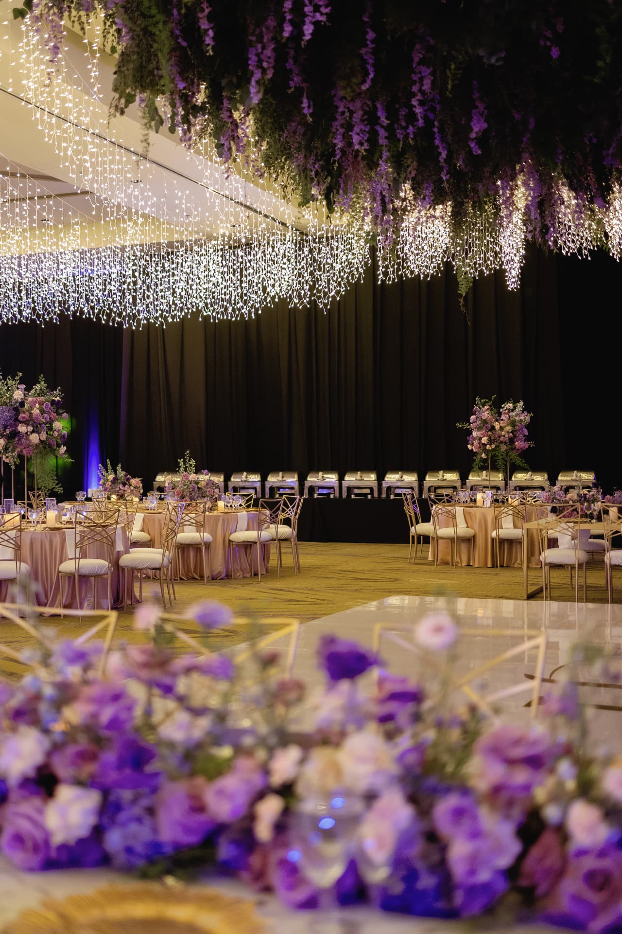 Ballroom reception with purple lighting and a floral ceiling