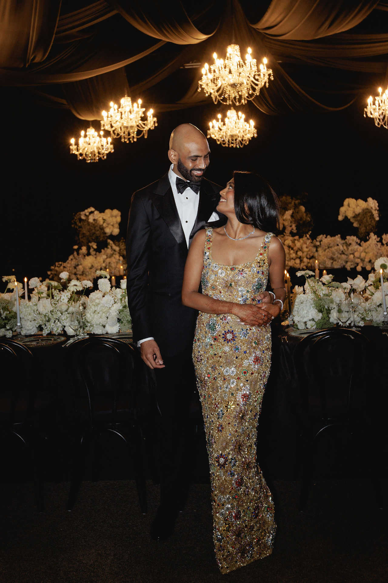 Shivam and Prarthi together beneath chandeliers at the reception