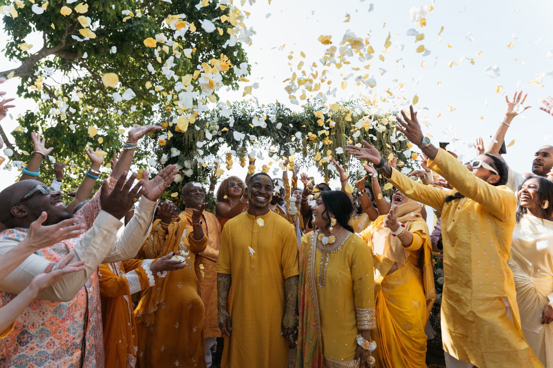 Cynthia and Azriel surrounded by loved ones beneath falling flower petals