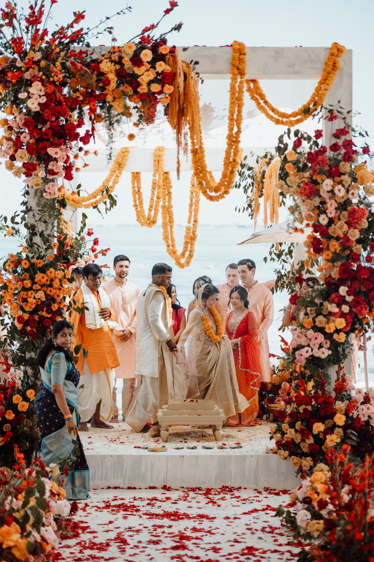 Seaside ceremony with floral arch, marigolds, the couple and their guests
