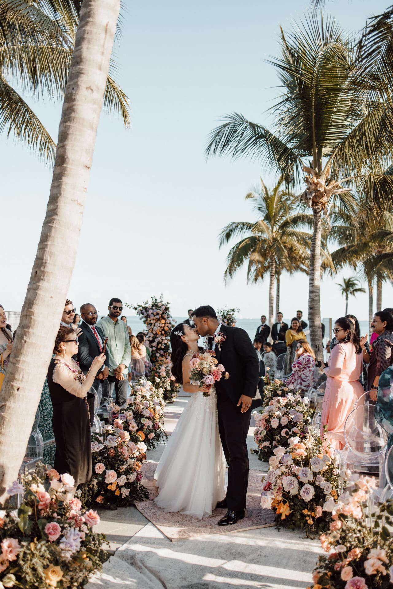 Beach ceremony kiss beneath the palm trees