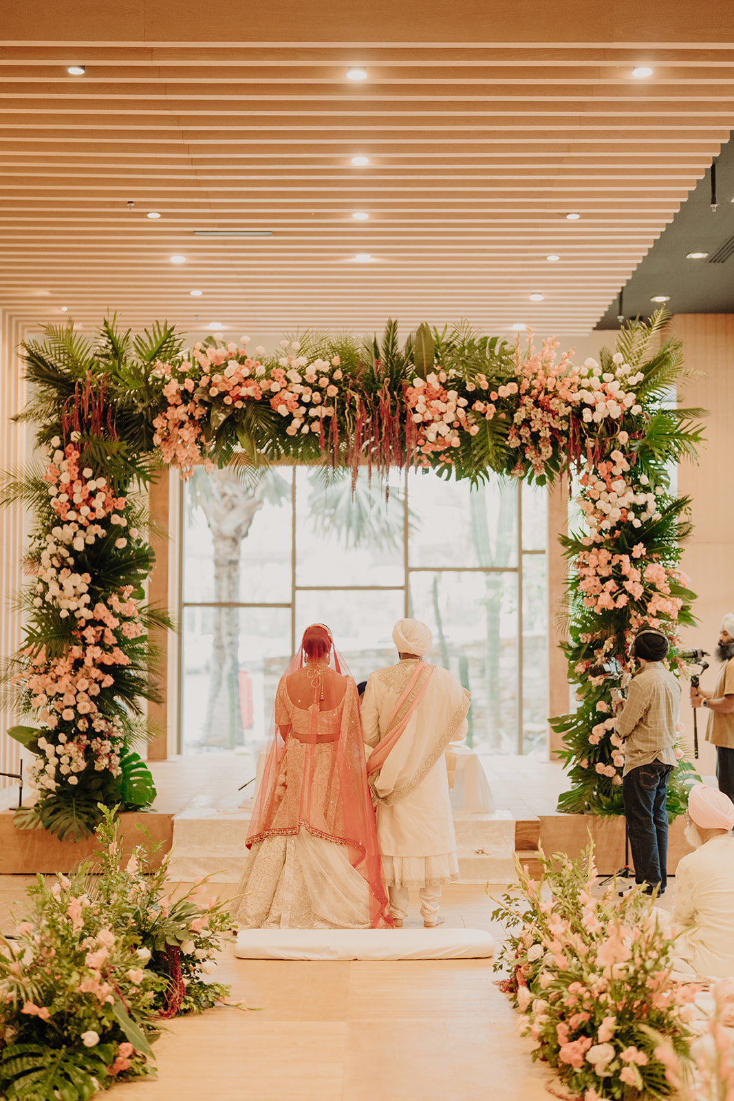 Sneha and Apoorv beneath a floral ceremony arch